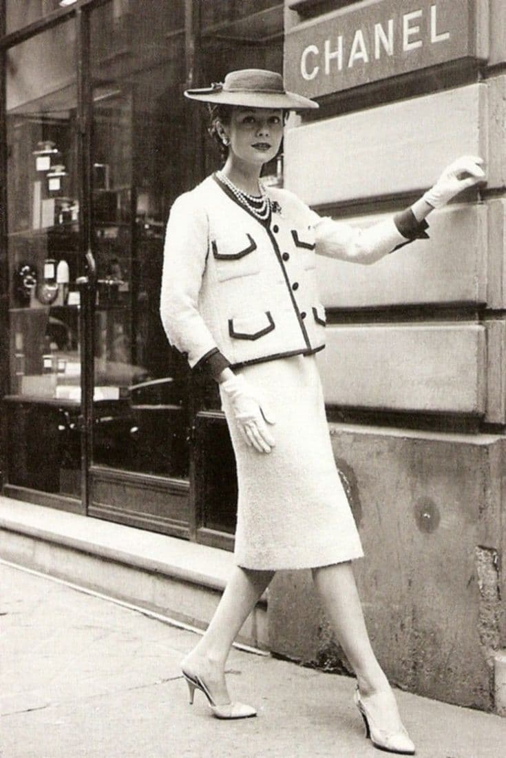 Woman in a classic Chanel tweed suit and gloves outside the Chanel boutique