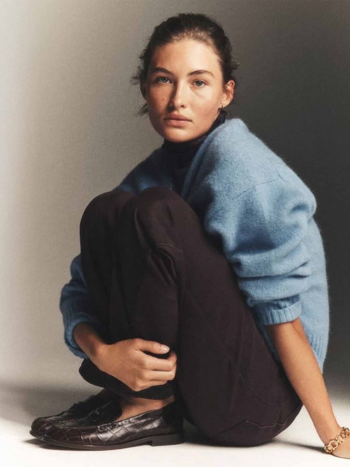 Woman in a blue sweater and brown trousers seated on the floor, Reflora customer archetype