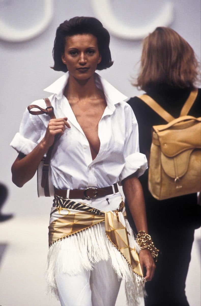 Runway look with an open white shirt and a gold fringed hip scarf, product line inspiration